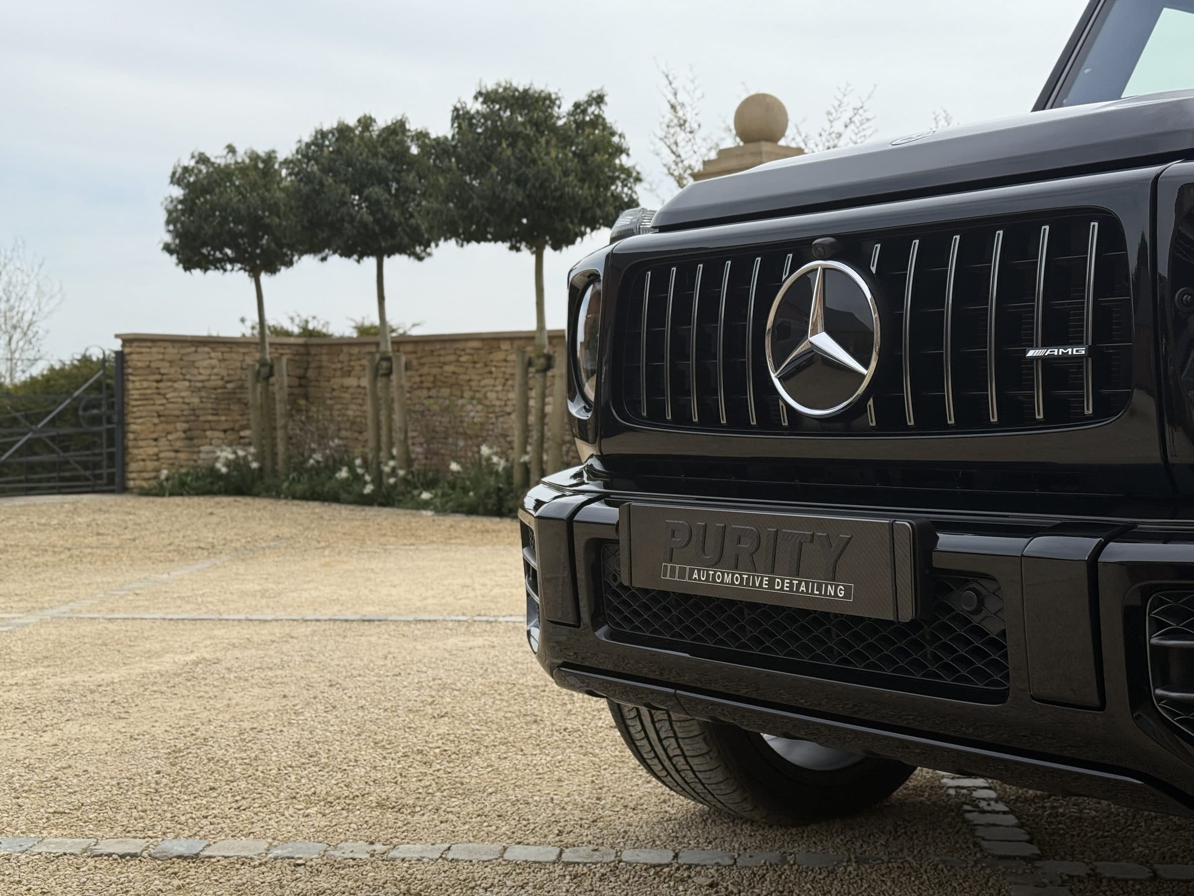 Front of a black Mercedes-AMG G 63 on a gravel courtyard