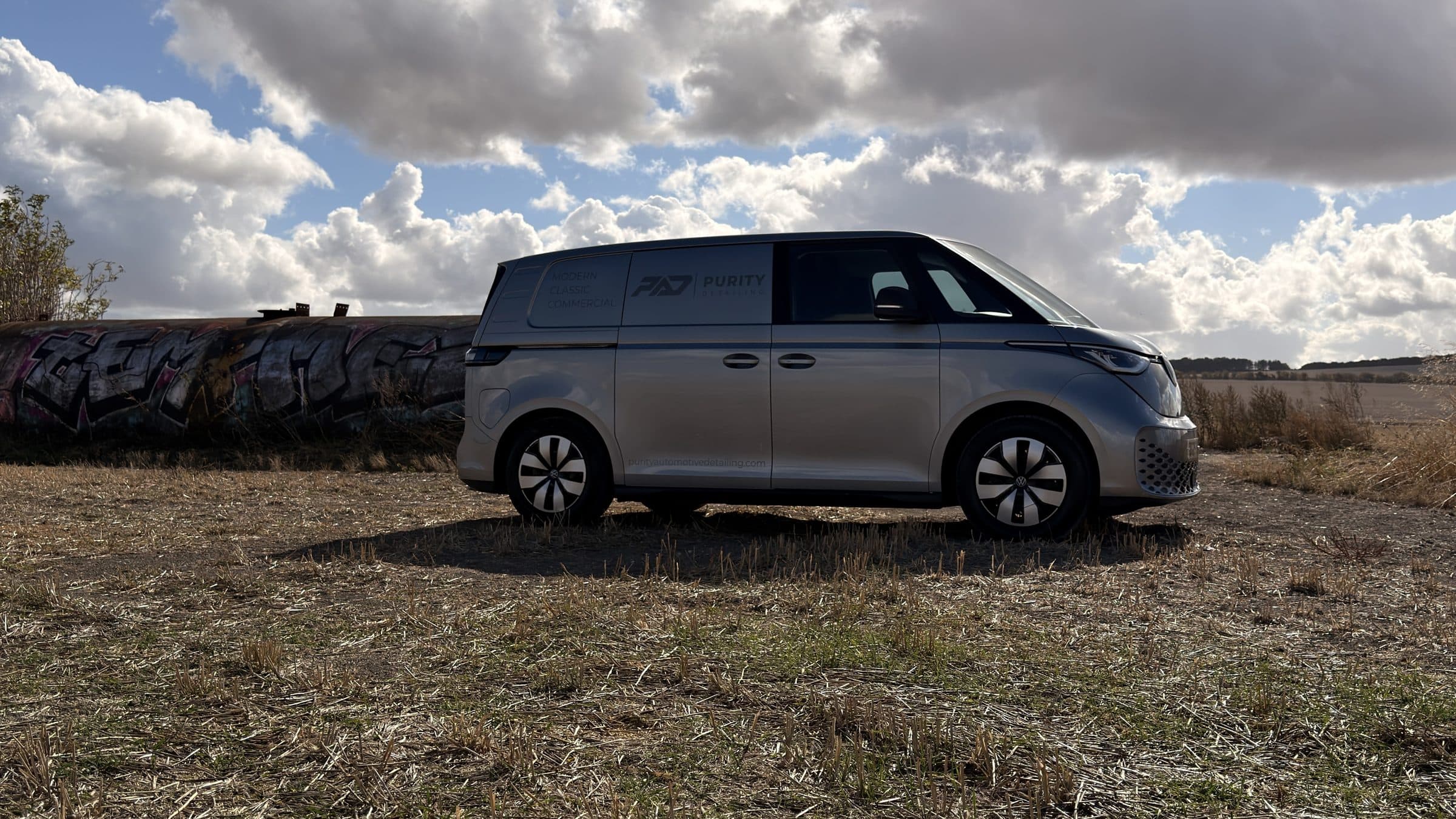 Purity Detailing's silver Volkswagen ID. Buzz van parked on stubble under a cloudy sky